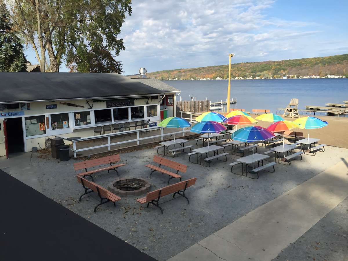 Outdoor bar and seating area at Beachcomber with colorful umbrellas and views of Conesus Lake.