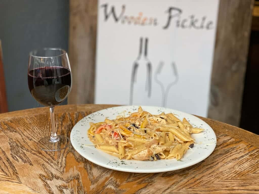 creamy cajun pasta with chicken, tomatoes and shredded cheese with a glass of red wine