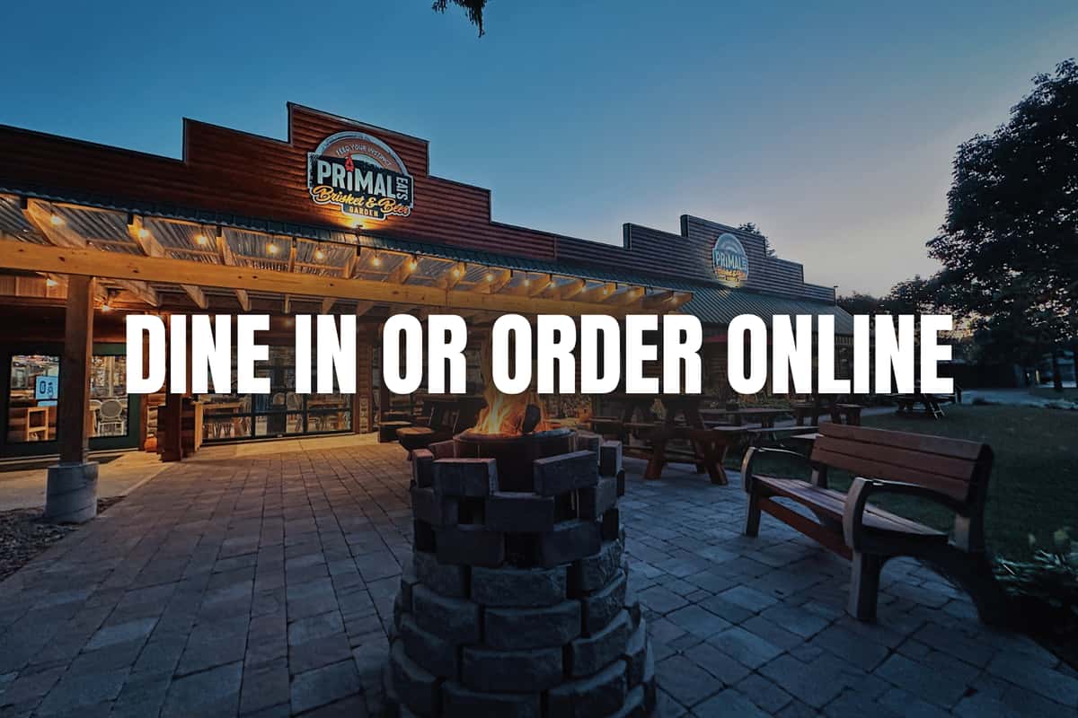 Exterior of a restaurant called "Primal Eats" at dusk, with campfire burning. Text says: Dine in or Order online, keeps you on this site.