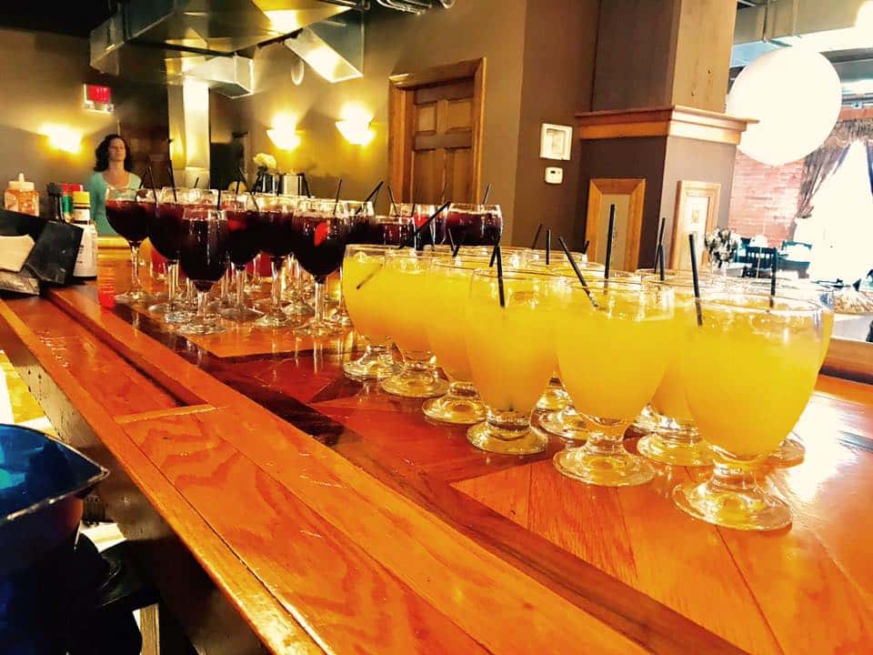 mimosas and sangria lined up on the bar ready to be served for a large party