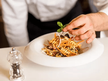 chef placing greens on dish