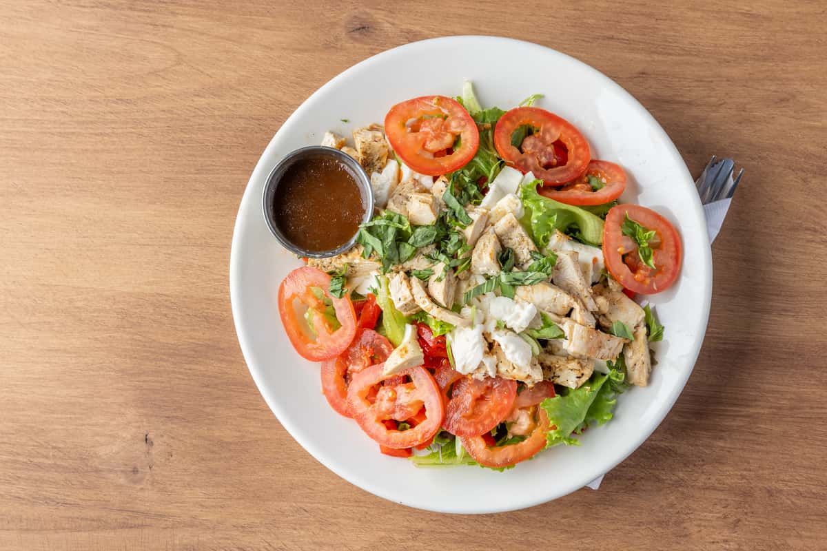 Grilled chicken salad with fresh tomatoes, mixed greens, and house dressing, light American lunch option
