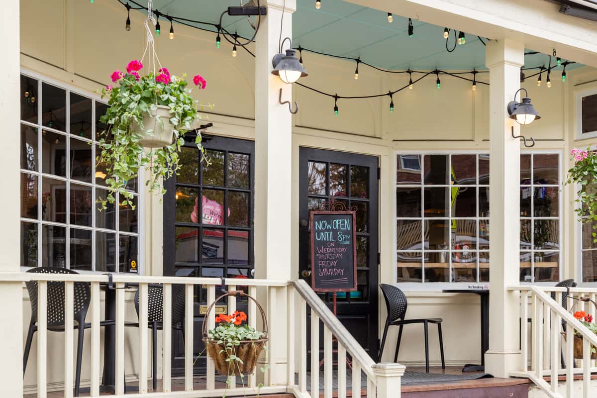 Charming restaurant patio entrance with hanging flower baskets, string lights, and cozy outdoor seating at One Oakland in Warwick NY
