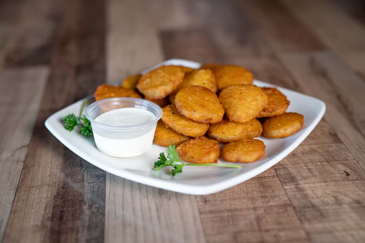 fried pickles with a side of ranch dressing on a white plate