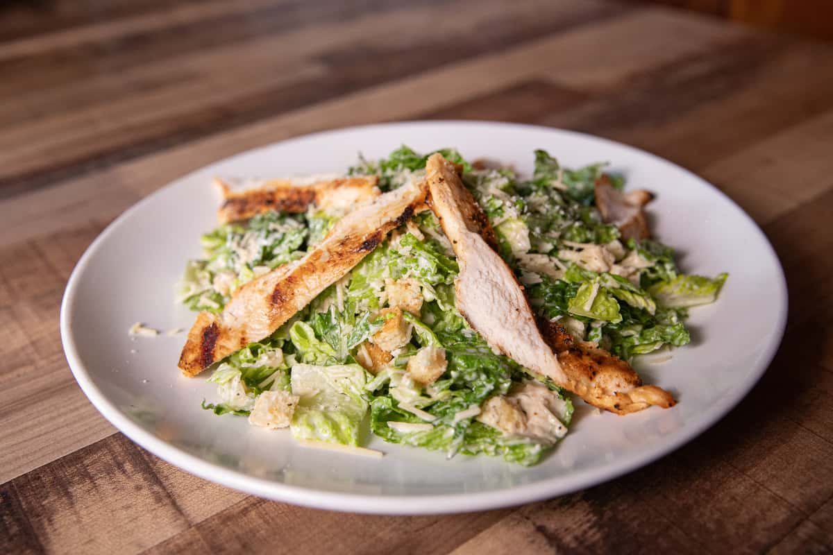 caesar salad with chicken on a white plate