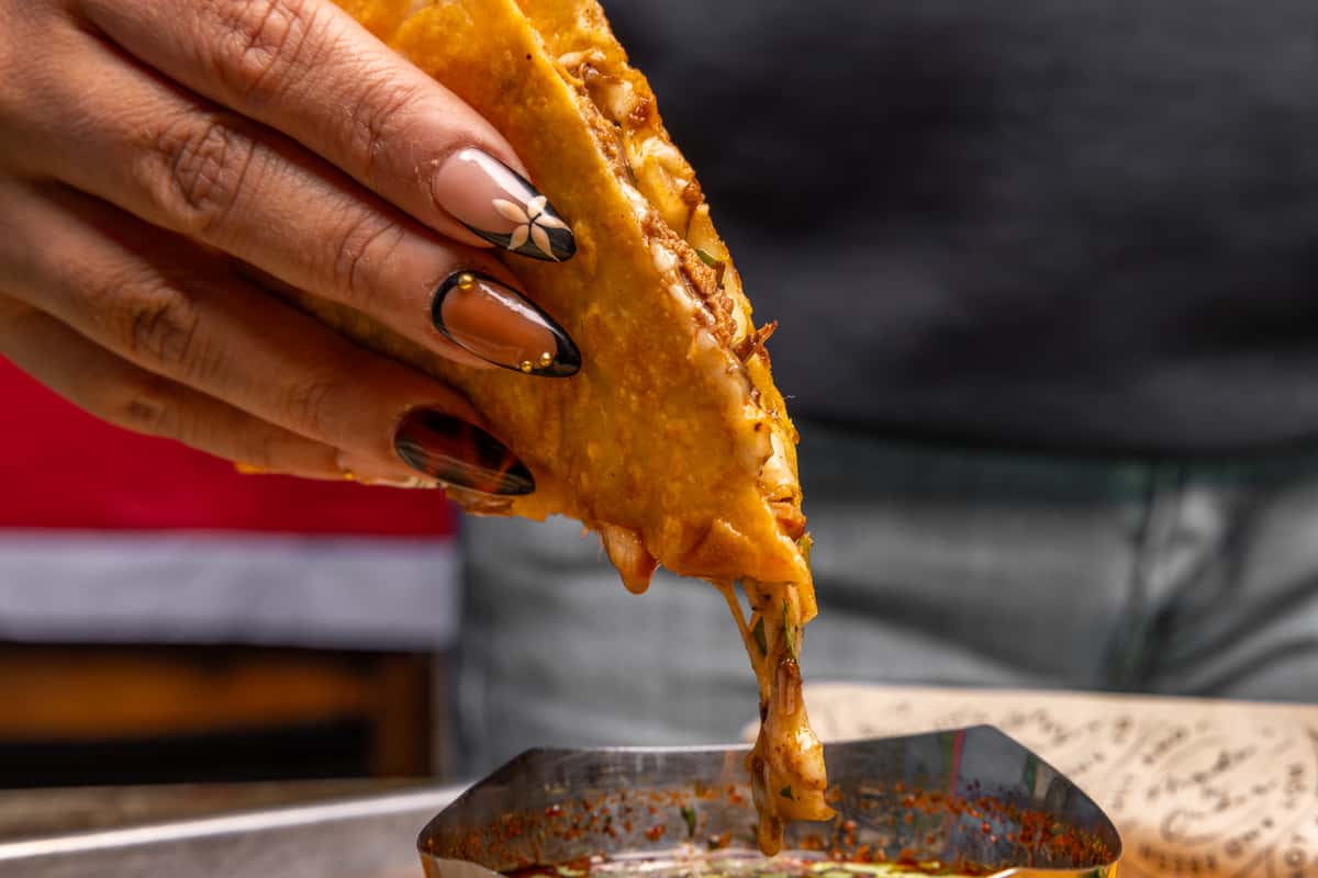 Close up of person dipping food into a sauce