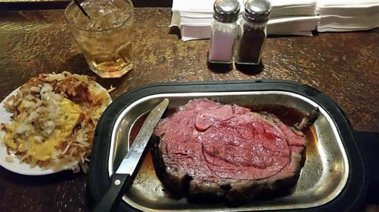 prime rib on a plate with a steak knife and salt & pepper shakers above the plate