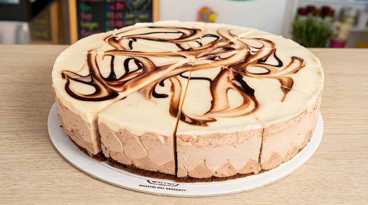 Round mocha cheesecake with white and dark chocolate swirl topping, sliced for serving.