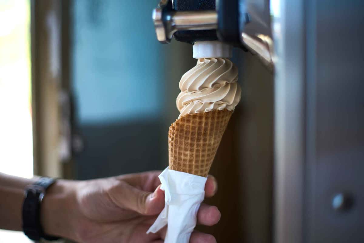 holding an ice cream cone while swirling a soft serve on it