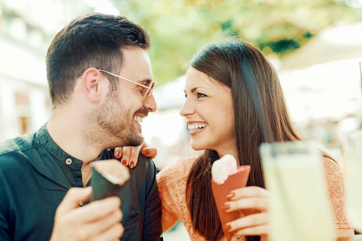 a couple holding two ice cream cones smiling