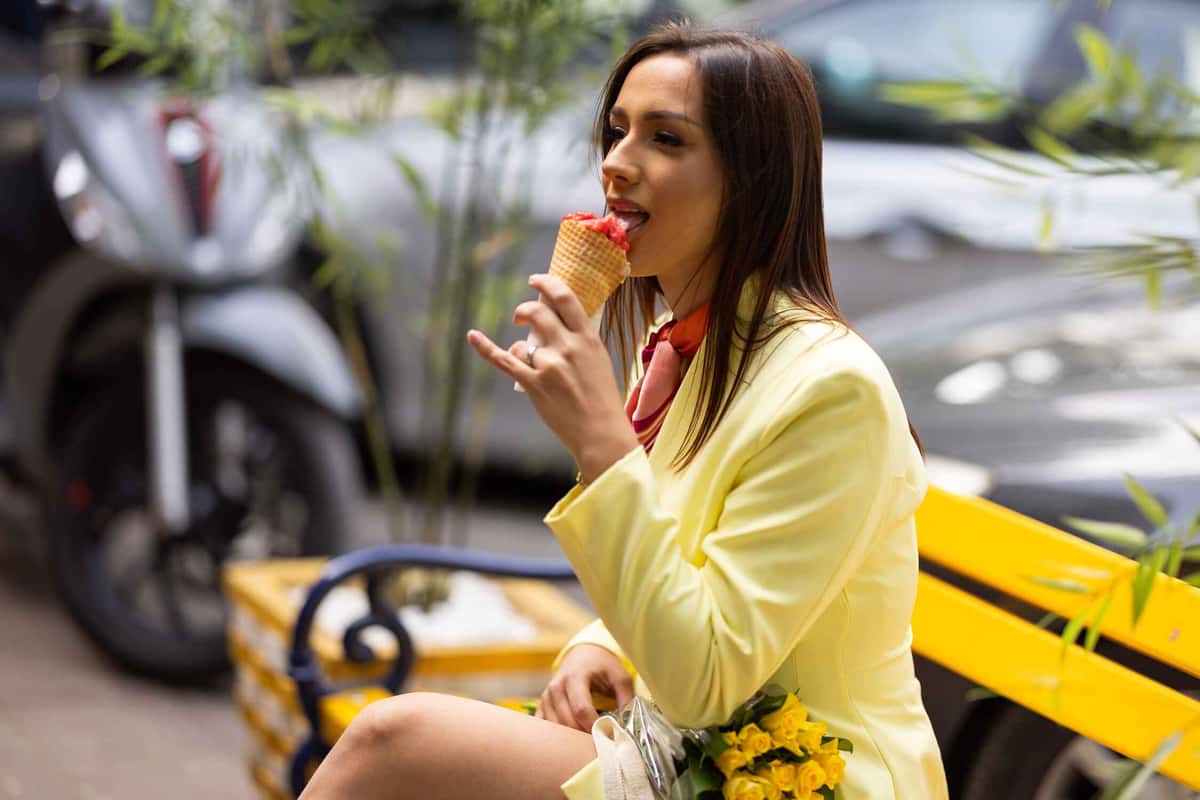 woman sitting on a bench eating an ice cream