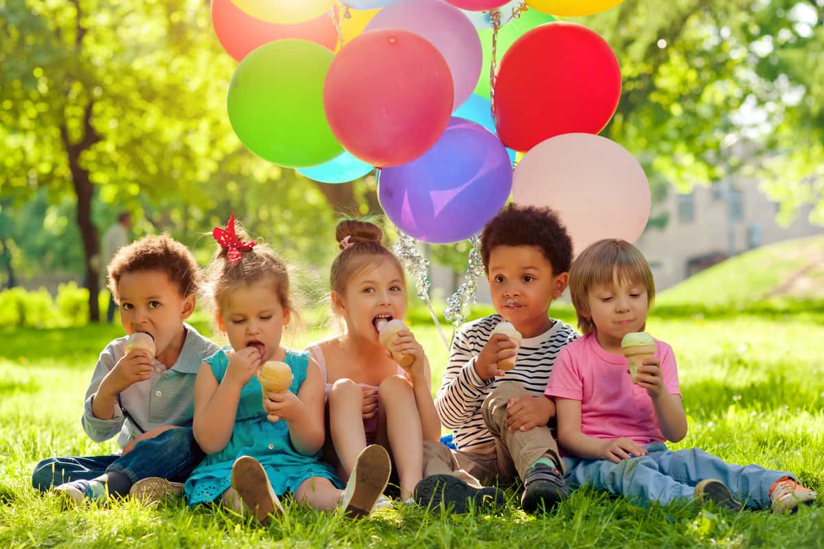 a group of kids eating desserts with balloons