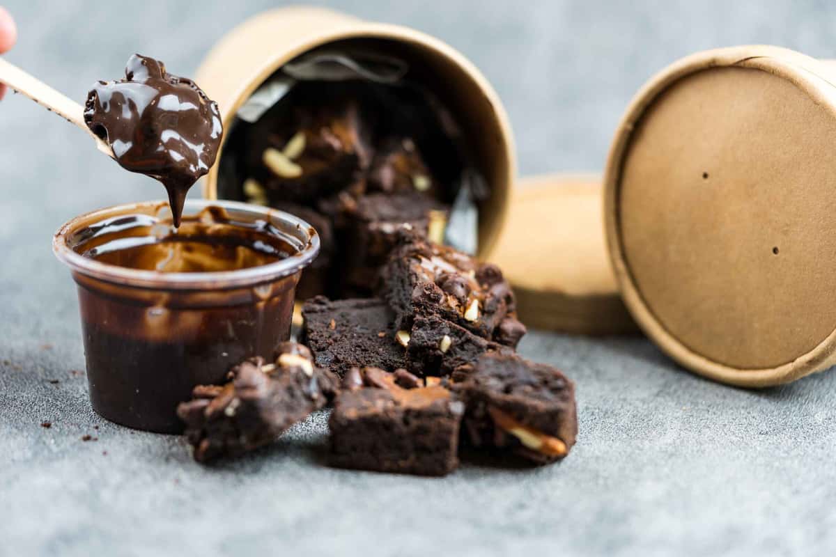 a container of brownies with fudge beside it