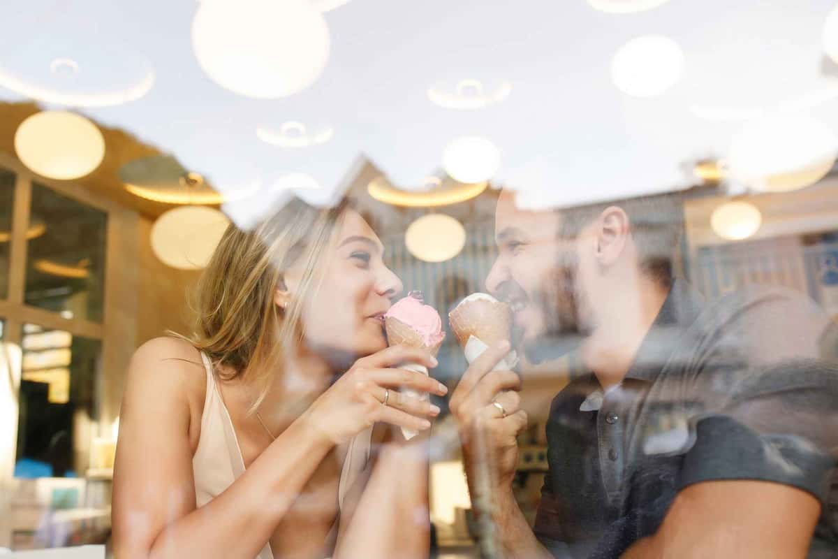 couple eating an ice cream behind a glass wall