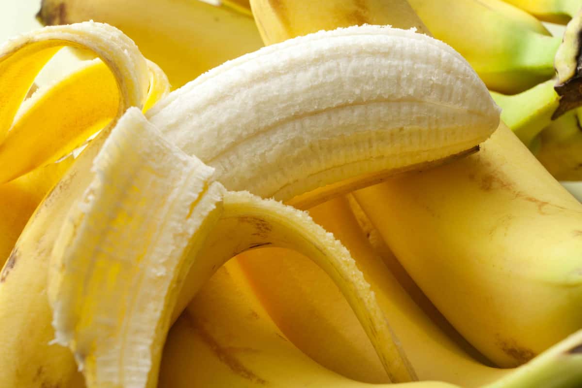 peeled banana behind unpeeled banana