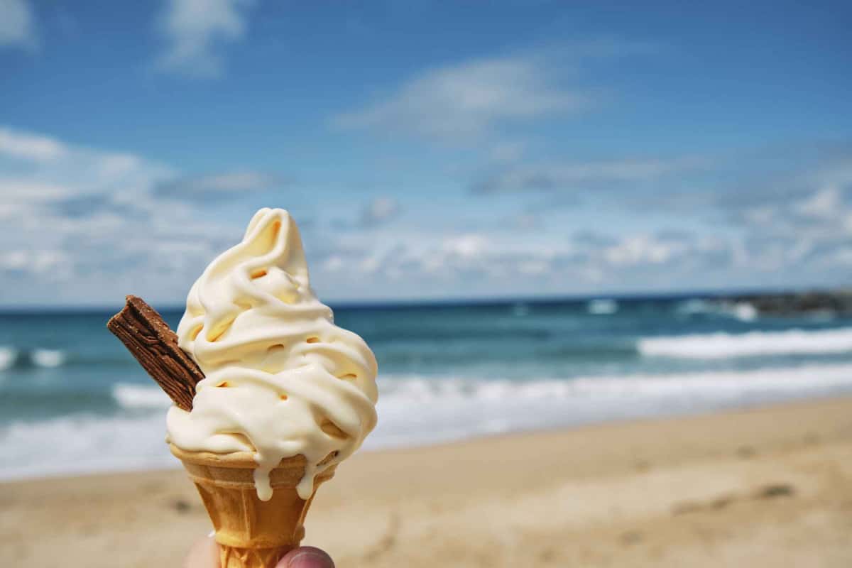a soft serve in a cone in front of the beach