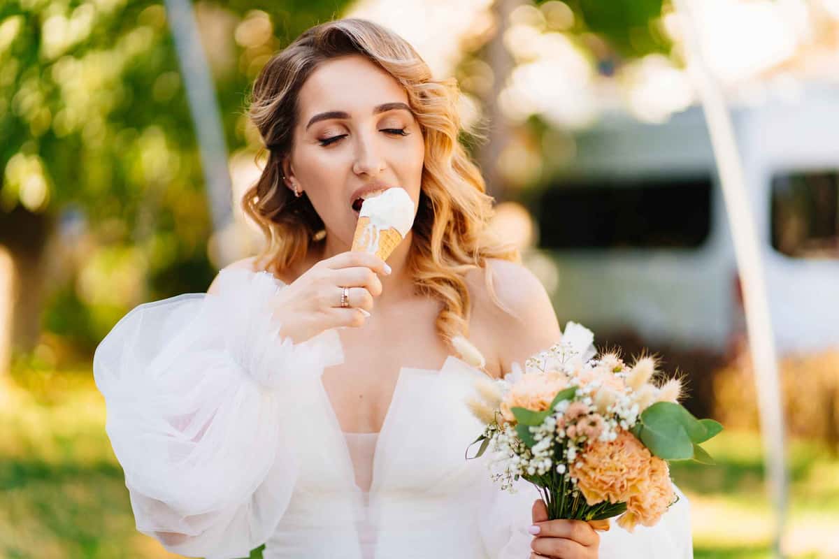 Bride holding a bouquet and eating ice cream