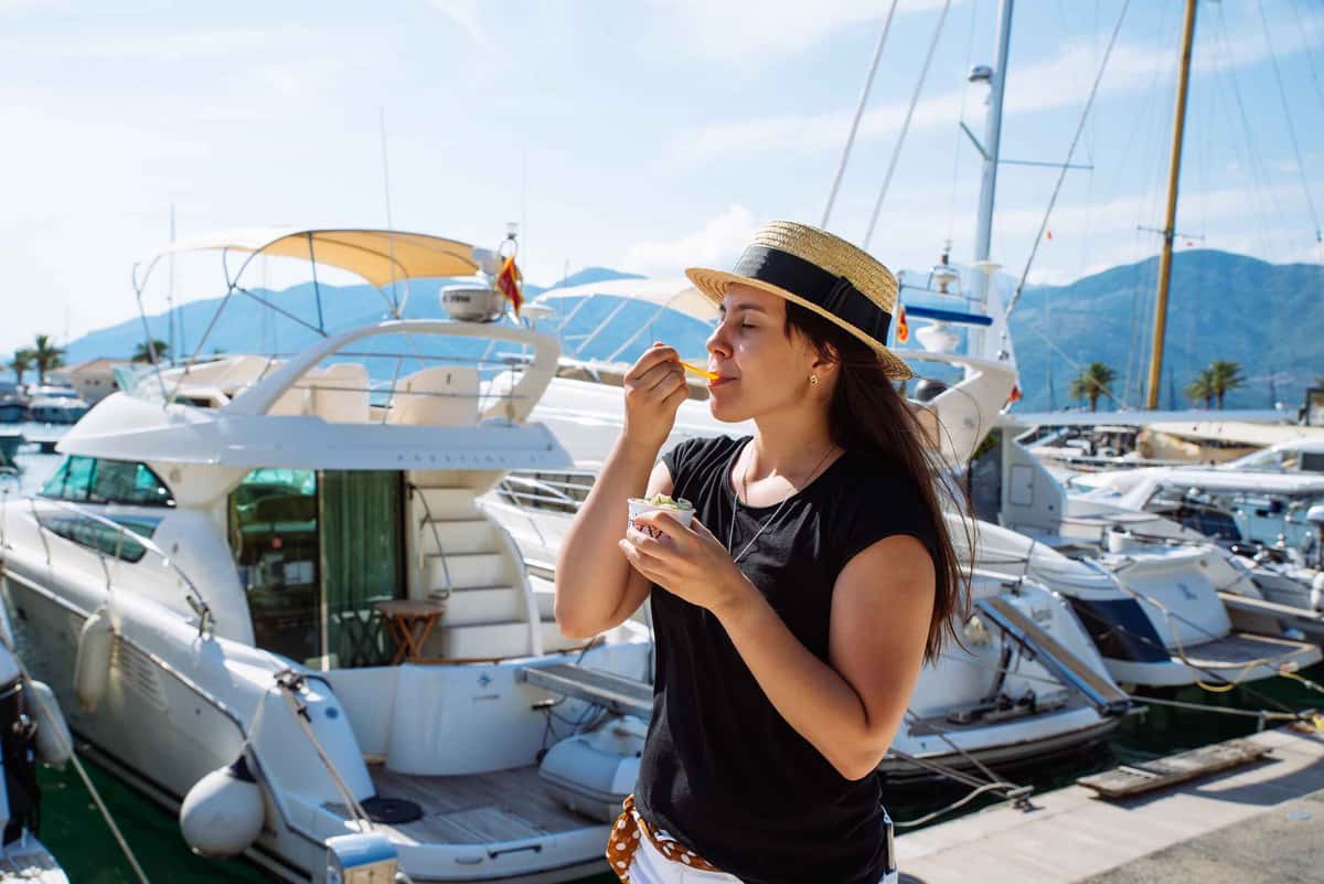 a woman eating ice cream by some boats