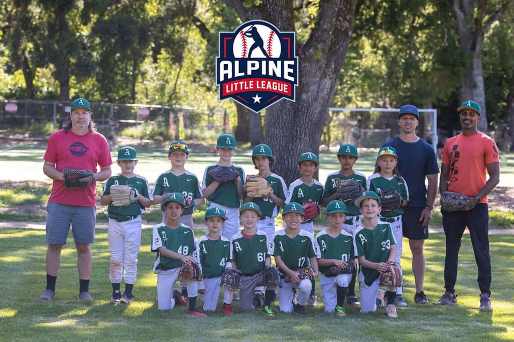 Alpine Little League youth baseball team poses with coaches on a grassy field, players in green uniforms holding gloves under trees