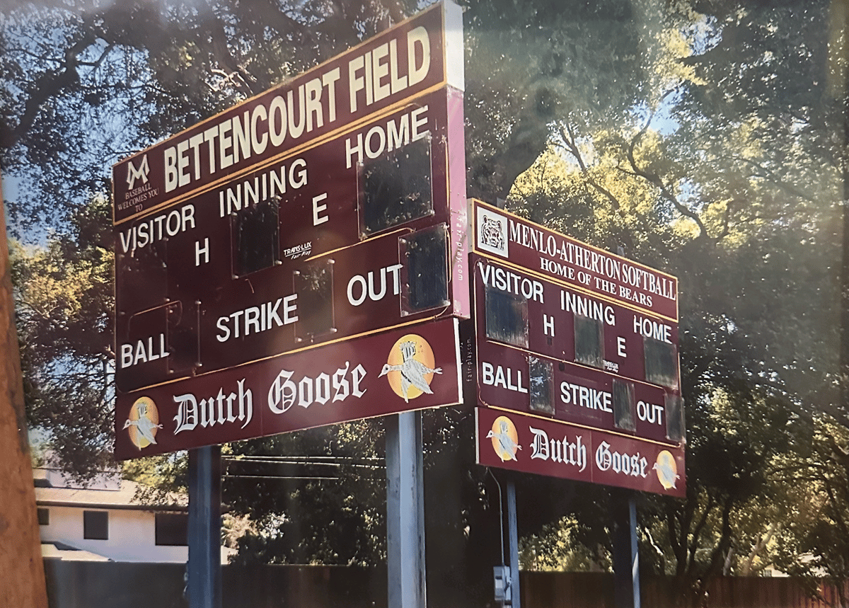 Two maroon baseball scoreboards at Bettencourt Field under trees, showing visitor and home innings with Dutch Goose branding