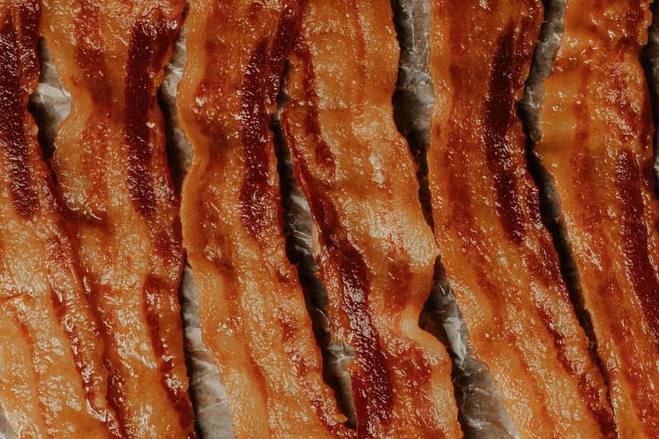 Close-up of crispy oven-cooked bacon strips with rich, smoky glaze and sizzling texture – classic breakfast meat perfect for brunch menus or burger and pizza toppings.