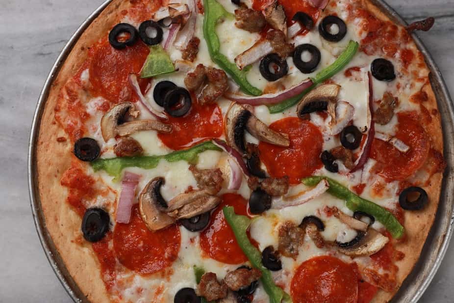 Supreme pizza topped with pepperoni, Italian sausage, black olives, mushrooms, green bell peppers, and red onions over melted mozzarella and rich tomato sauce on a hand-tossed crust – classic combination pizza perfect for an Italian-American pizzeria menu.