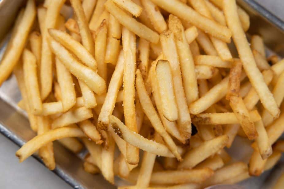 Close-up of crispy golden French fries with a light salt seasoning, served in a metal tray – classic American side dish perfect for burgers, sandwiches, and casual restaurant menus.