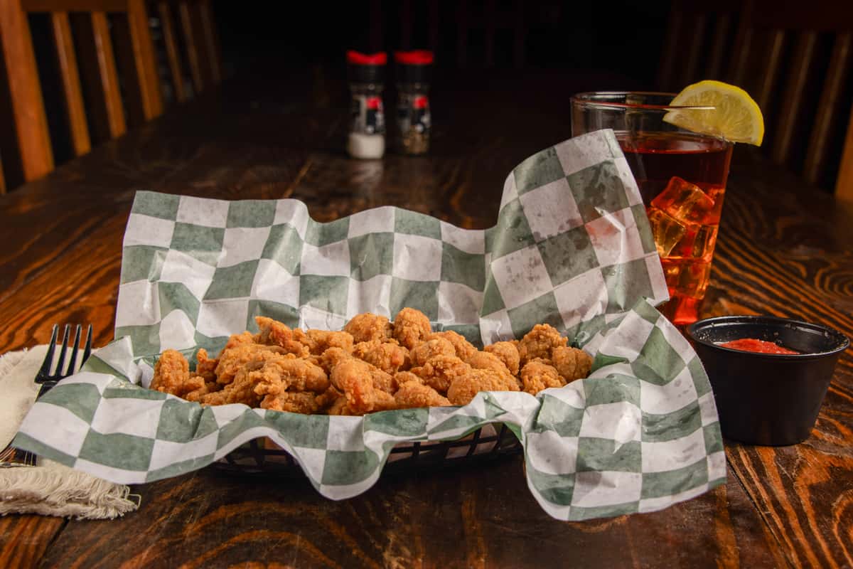 Angled view of fried crawfish tails with dipping sauce and drink at Blackwell Revival in Atkins, Arkansas
