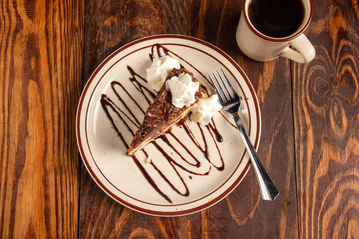 Top view of cheesecake slice with chocolate drizzle and whipped cream at Blackwell Revival in Atkins, AR