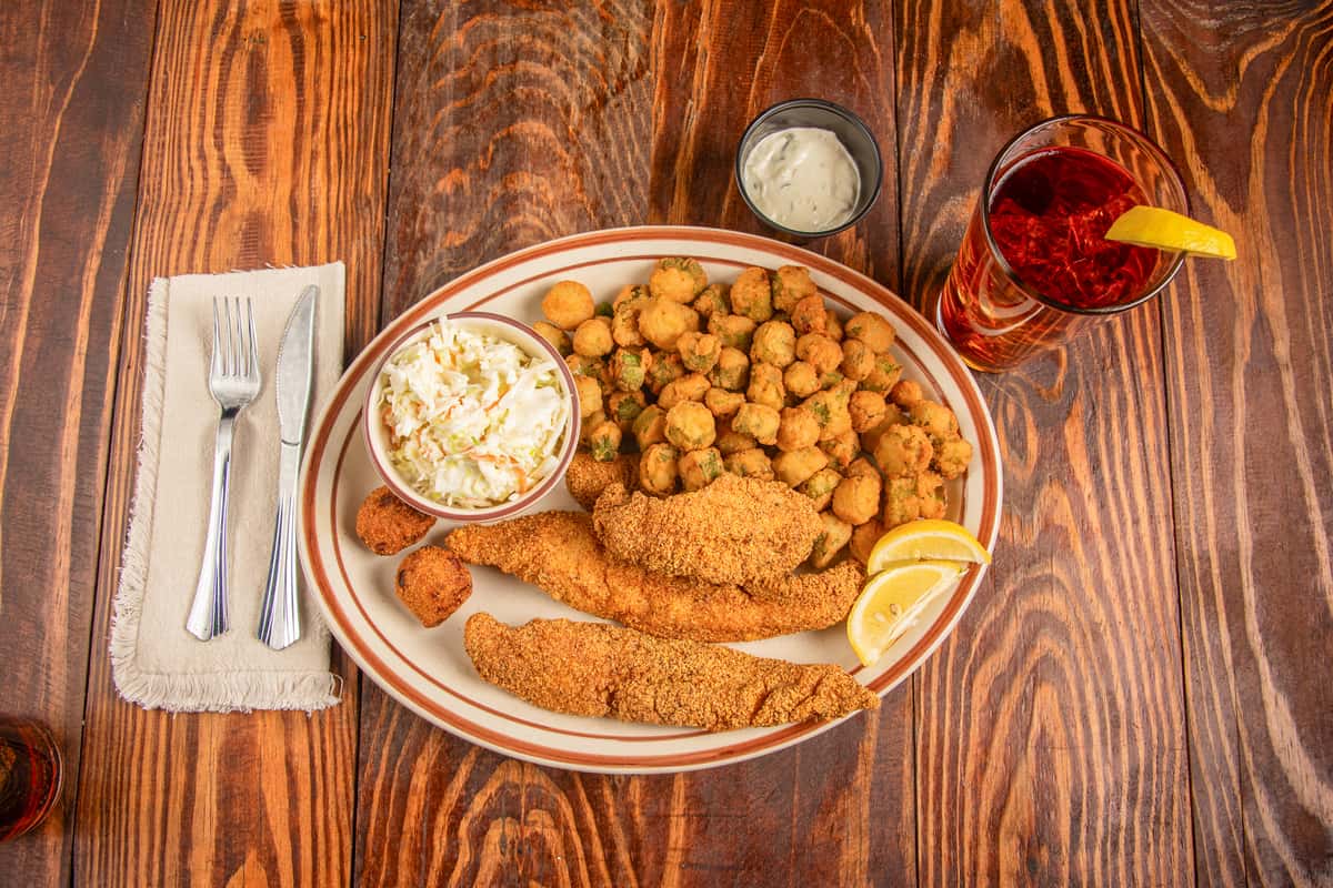 Top view of fried catfish entrée with hushpuppies, coleslaw, and sides at Blackwell Revival in Atkins, Arkansas
