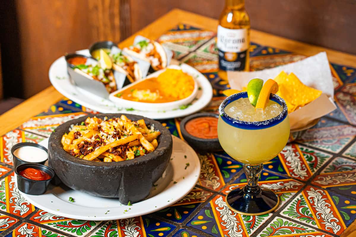 Different Mexican dishes with a margarita and beer