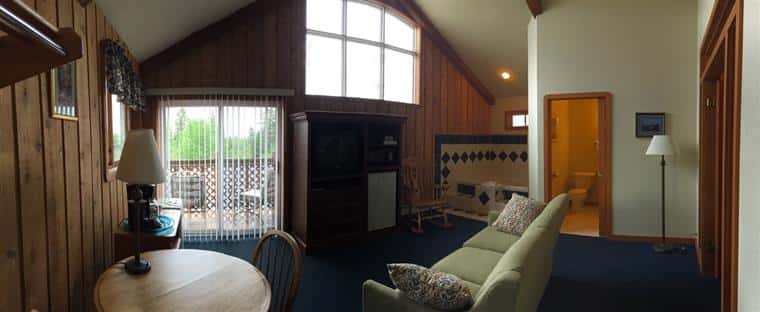 Honeymoon suite with high ceilings, sliding door to balcony, table and chairs, couch.