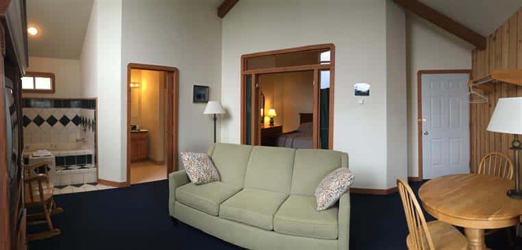 Honeymoon suite showing couch, bedroom, closets, table and chairs.