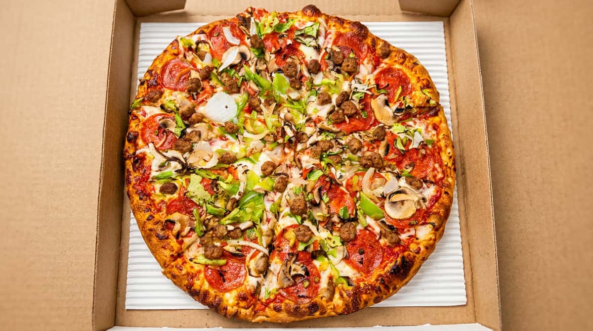 Pepperoni pizza with sausage, green peppers, onions, and mushrooms in a cardboard box.