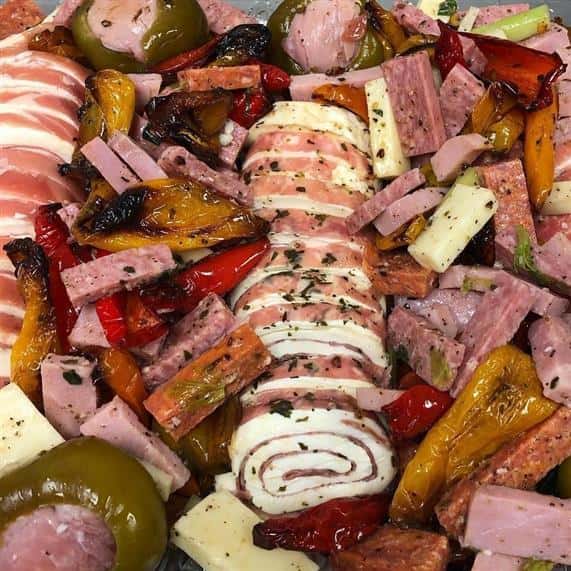 antipasto platter with various types of meats and cheeses with olives and stuffed peppers