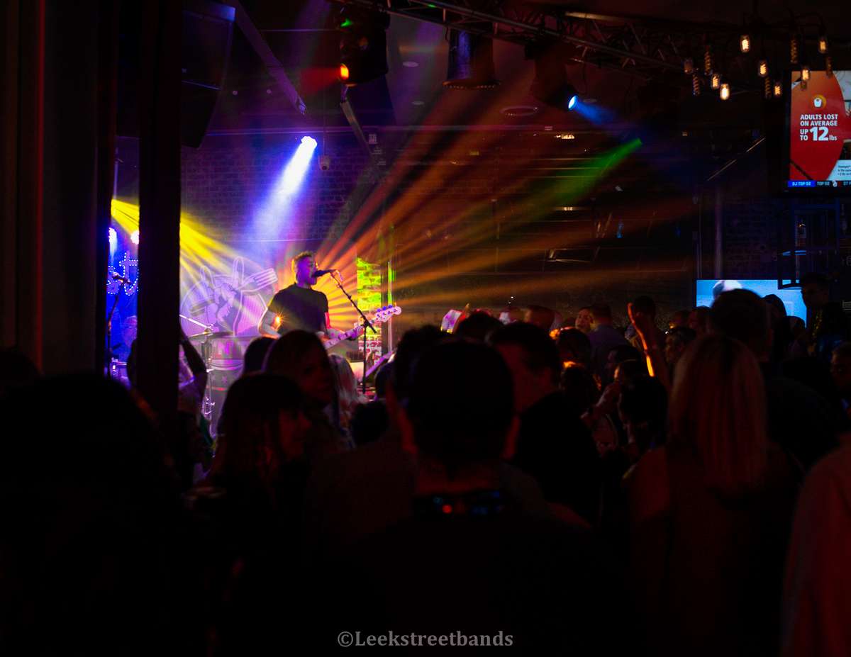 Musicians on Rock 'N' Taco stage performing to an enthusiastic crowd with stage lights strobing in background.