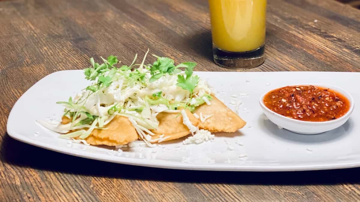 Two corn turnovers with green cabbage, queso fresco, Mexican cream & a side of molcajete sauce, stuffed with your choice of cheese & epazote, mushroom or shredded chicken.