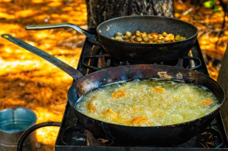 two frying pans on a stove in the woods