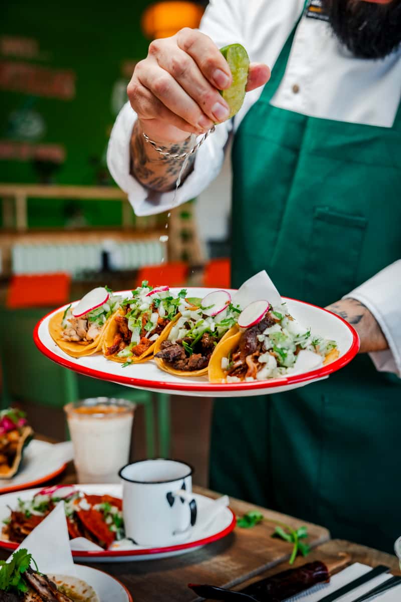 Chef squeezing a fresh lime over a plate of beef tacos