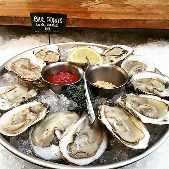 platter of oysters on the half shell over ice with dipping sauces