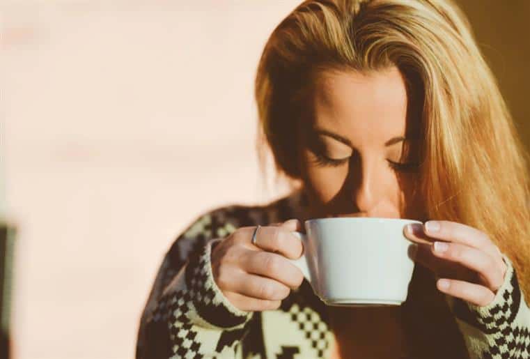 woman taking a sip of her coffee