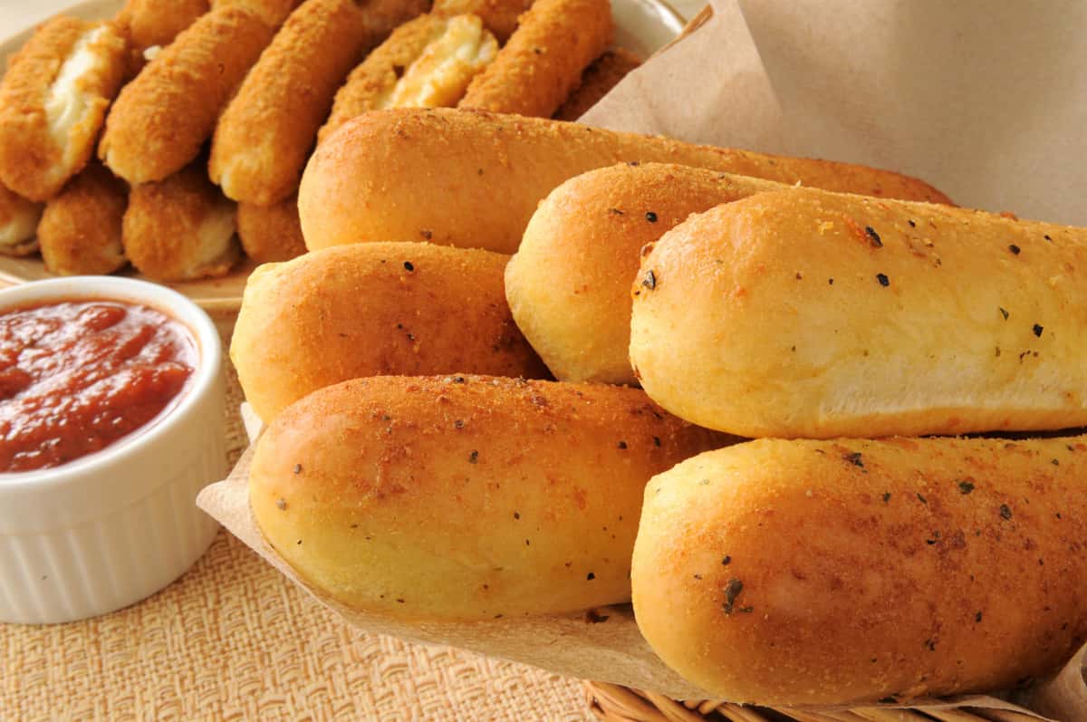 Golden garlic breadsticks and crispy mozzarella sticks served with a side of marinara dipping sauce in a cozy appetizer basket.