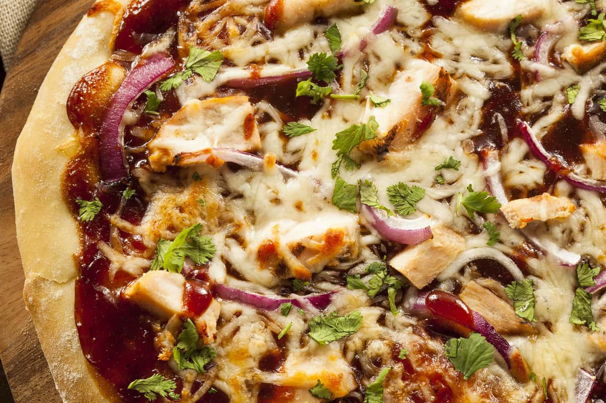 BBQ chicken pizza topped with mozzarella, red onions, cilantro, and tangy barbecue sauce on a golden crust.