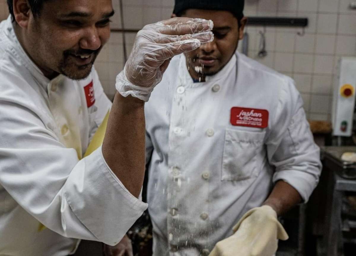 Chefs preparing fresh Indian cuisine in a professional kitchen using traditional cooking techniques