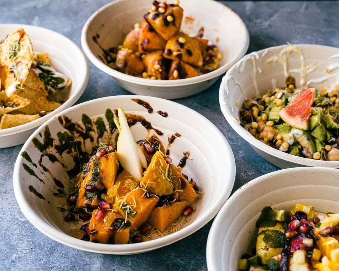 Modern Indian fusion small plates featuring roasted squash chaat with pomegranate seeds and chutneys, chickpea salad with fresh vegetables, grilled paneer bites, and creative vegetarian appetizers served in minimalist bowls on a contemporary restaurant table.