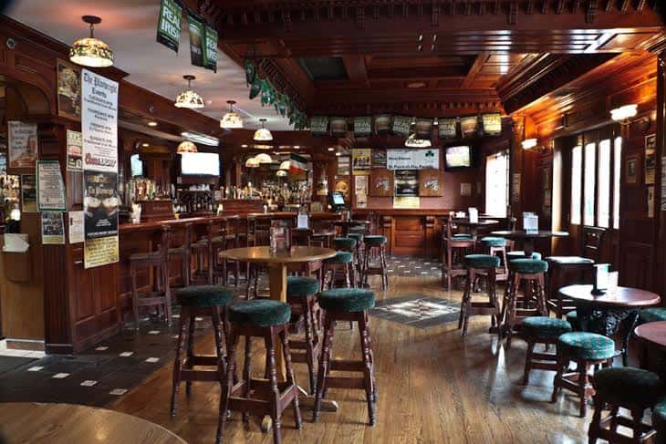 Wooden bar area with adjacent high-top dining tables.