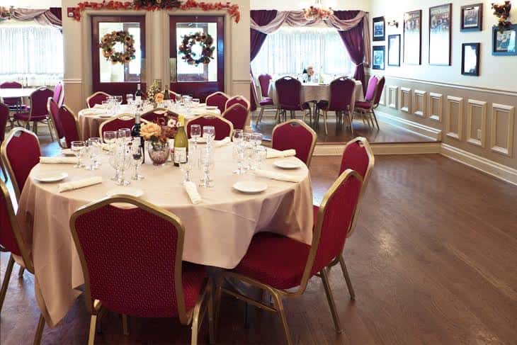 Inside photo of tables dressed with a tablecloth & napkins and plates surrounded by chairs