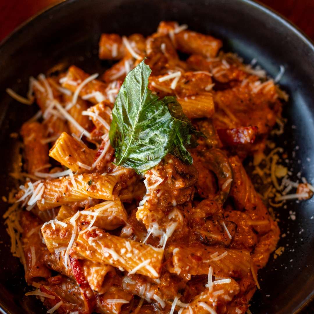 Creamy rigatoni pasta in a tomato-based sauce with Italian sausage, parmesan cheese, and fresh basil.