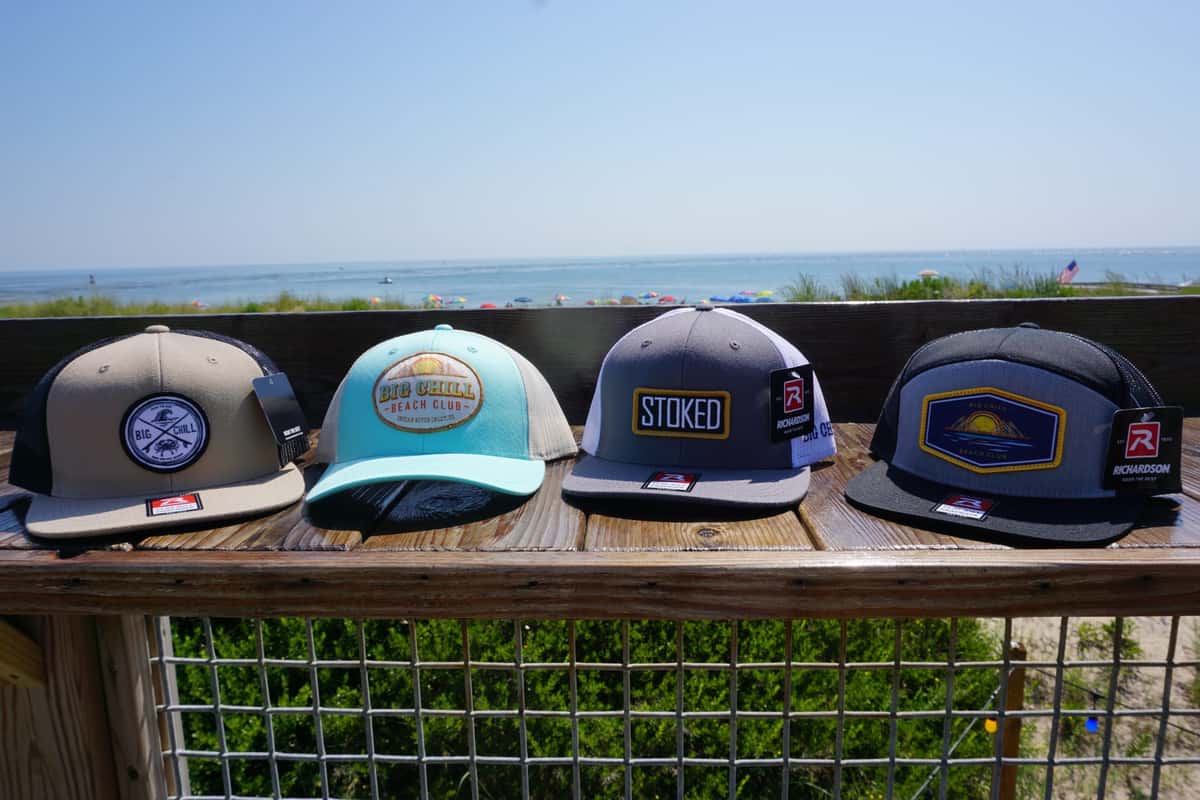 four branded ball caps on deck railing 