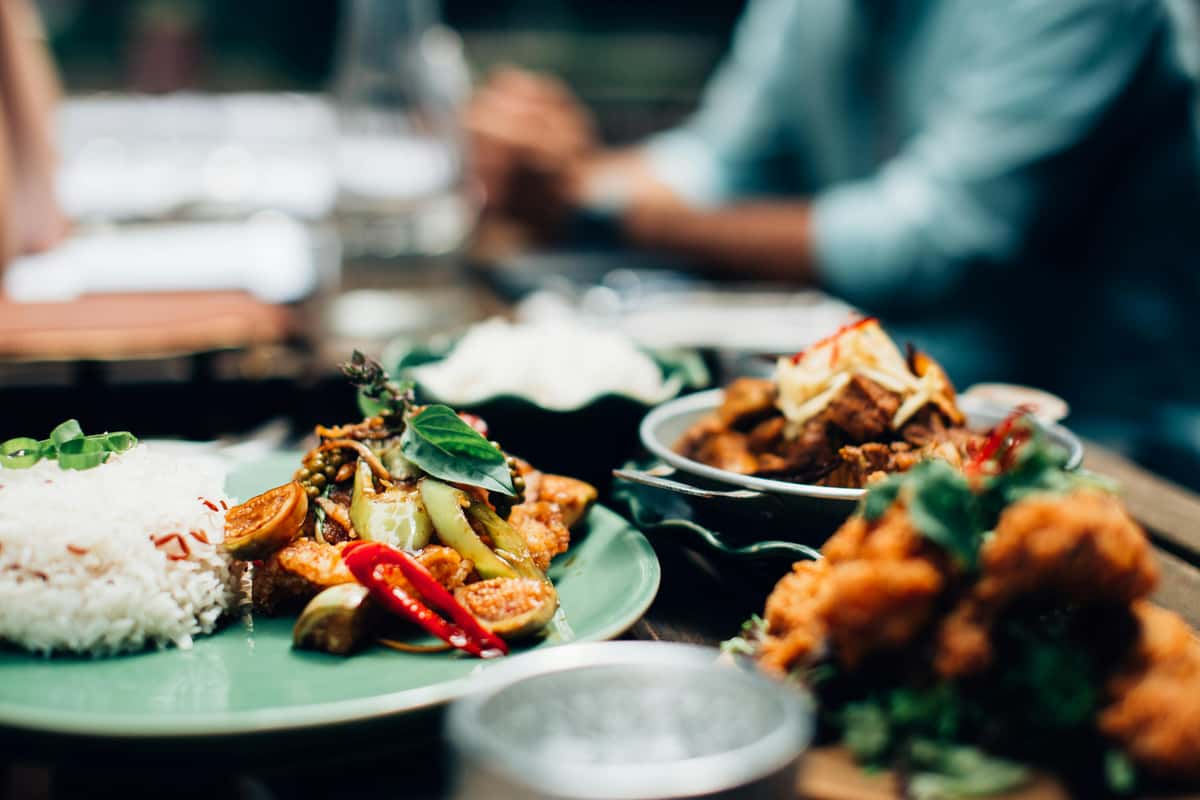 This close-up shot of a vibrant meal features a plate of white rice served alongside a colorful stir-fry with red chili peppers.